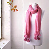 Faux fur pom pom pashmina winter scarf displayed on mannequin with window in background.