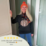 Woman in black sweater and orange hat modeling Halloween Pumpkin & Bat Silky Satin Striped Scarf.