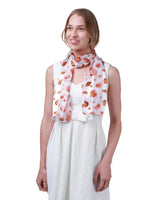 Woman wearing white dress and pumpkin silky satin striped scarf.