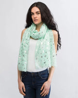Woman wearing oversized scarf with cow print and silver foil detail.