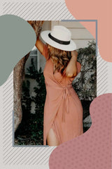 A flowing peach-colored wrap dress paired with a white sun hat.