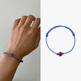 Hand holding Union Jack diamante friendship bracelet with red flower