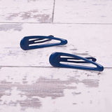 Two blue epoxy metal hair clips on a white floor from the school-ready durable hairpins set