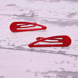 Two epoxy metal hair clips with red plastic handles on a white wooden floor, durable hairpins