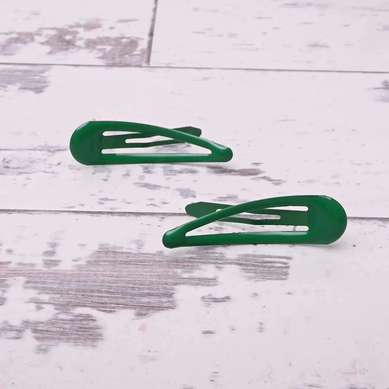 Two green epoxy metal hair clips on a white wooden floor - School-Ready Durable Hairpins