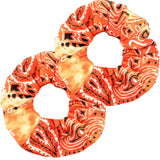 A close-up of a large, orange scrunchie with a paisley pattern to match paisley bandana scarf