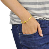 Woman wearing a yellow bracelet with a gold chain from Adjustable Diamante Ball Friendship Bracelet - Cotton Cord Design.