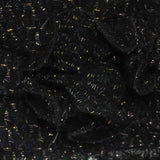 Shimmering knitted flower scarf with pile of black plastic waste