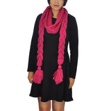 Woman in black dress wearing pink oversized long plait knitted scarf.