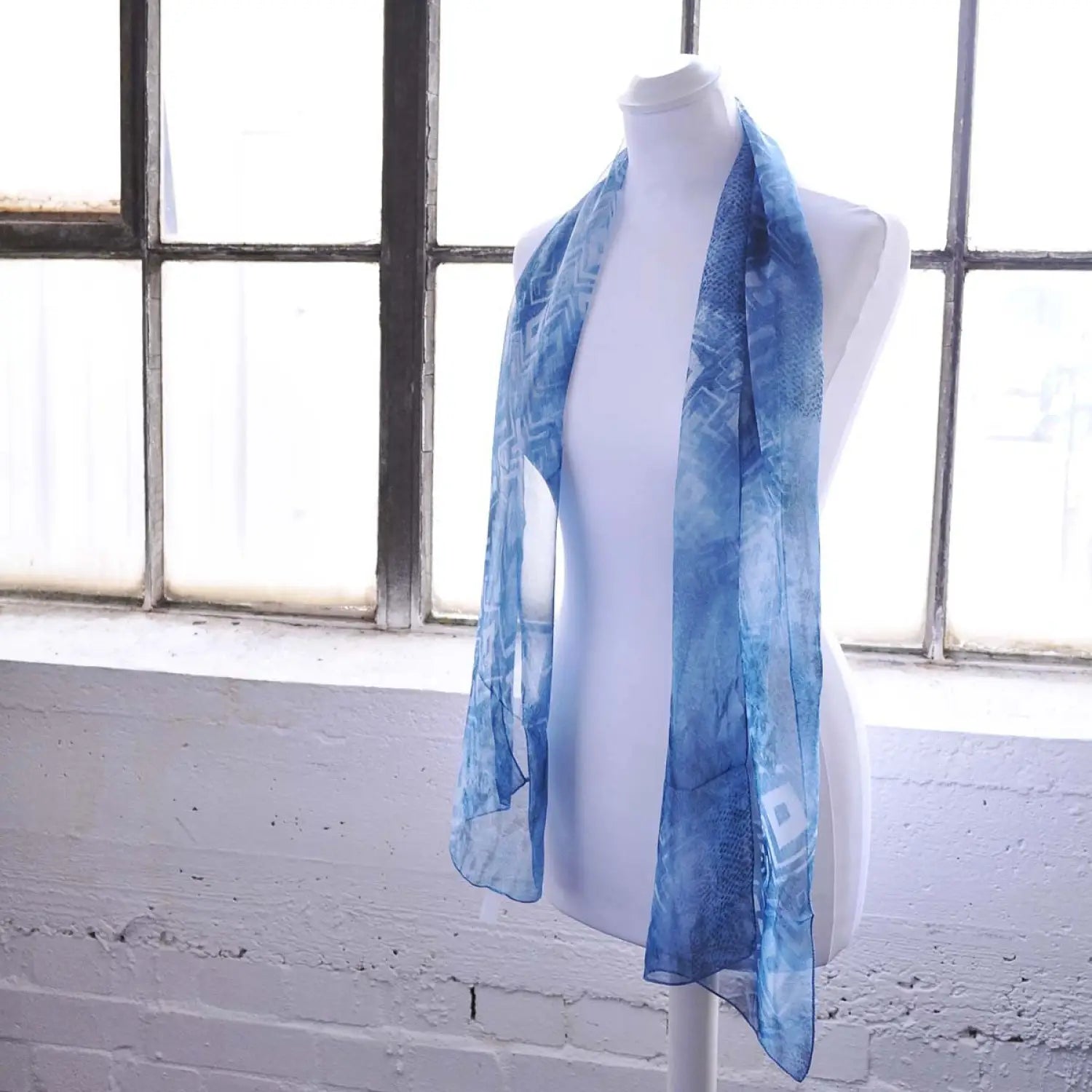 Blue and white Aztec animal snake print chiffon scarf displayed on mannequin