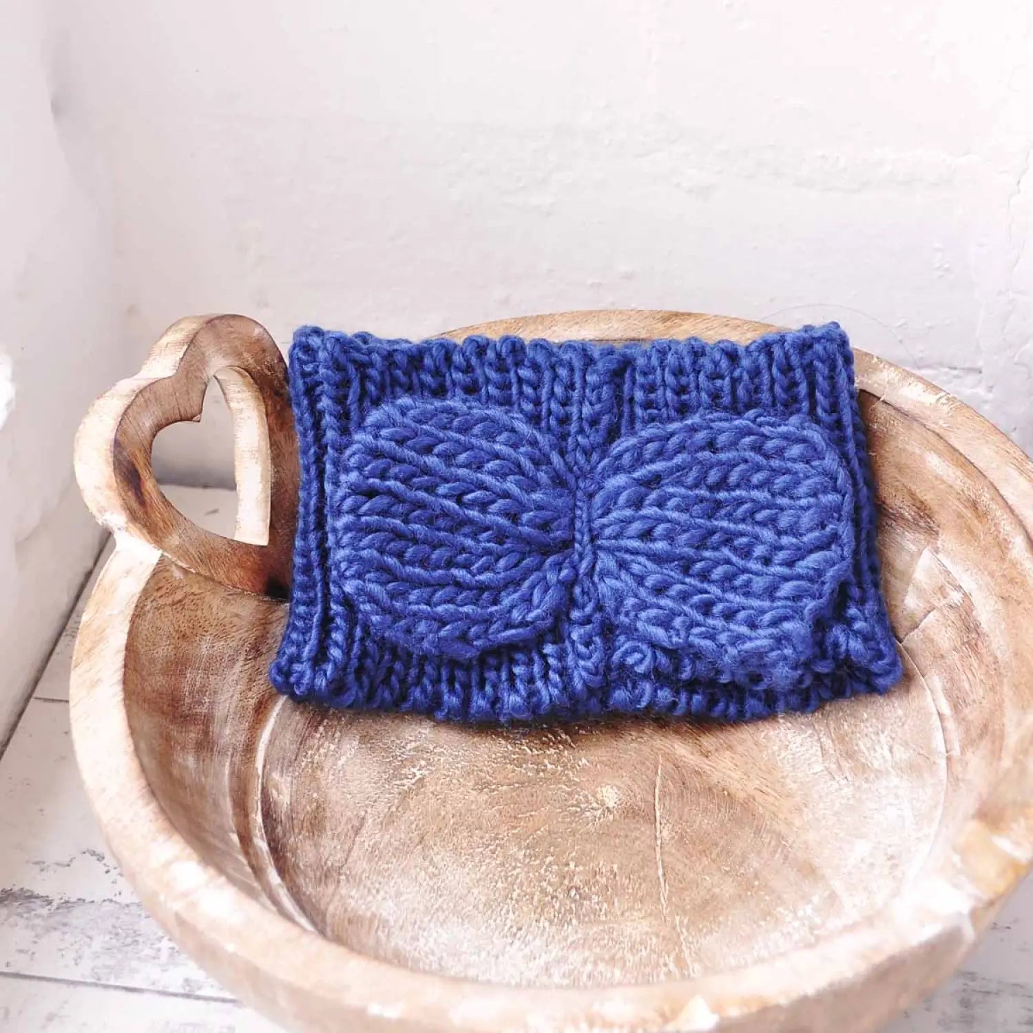 Blue knitted bow on wooden bowl featured in Bow-Detailed Knitted Headband for Autumn & Winter.