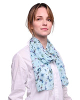 Woman wearing blue butterfly print scarf with floral pattern.
