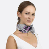 Woman wearing grey and purple floral small square scarf.