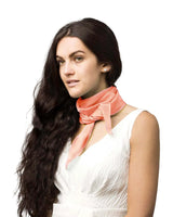 Woman wearing a white chiffon square scarf with a pink bow