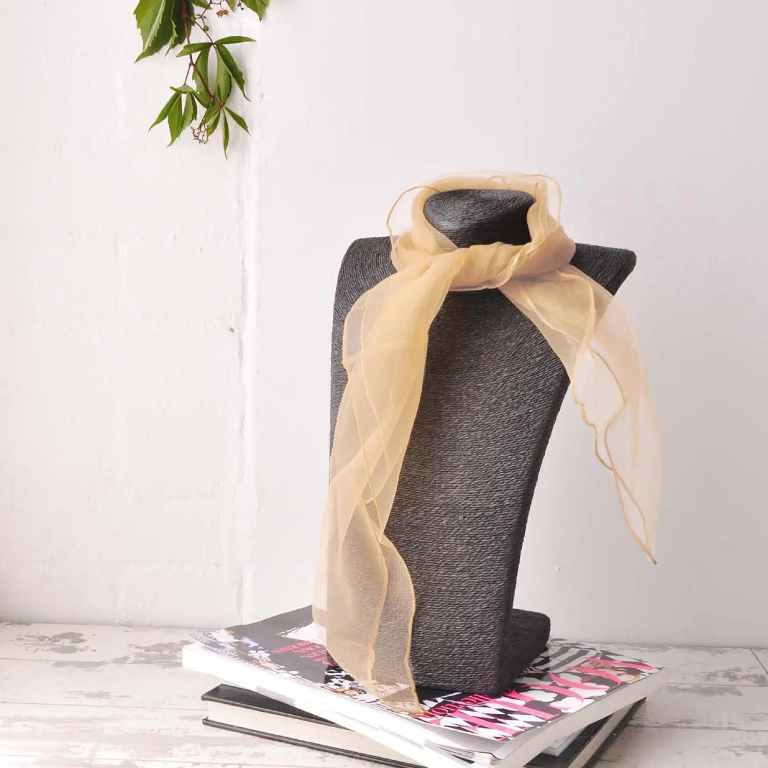Chiffon square scarf with black hat on stack of books