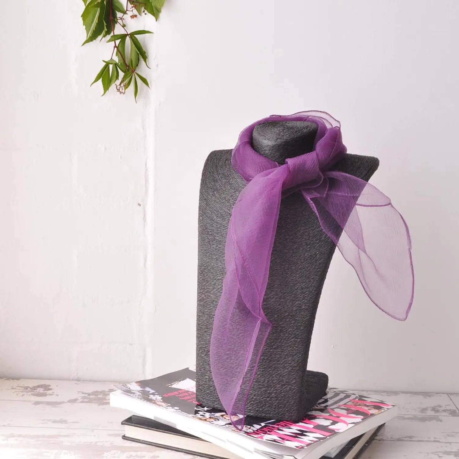Chiffon square scarf in purple color on top of a book.