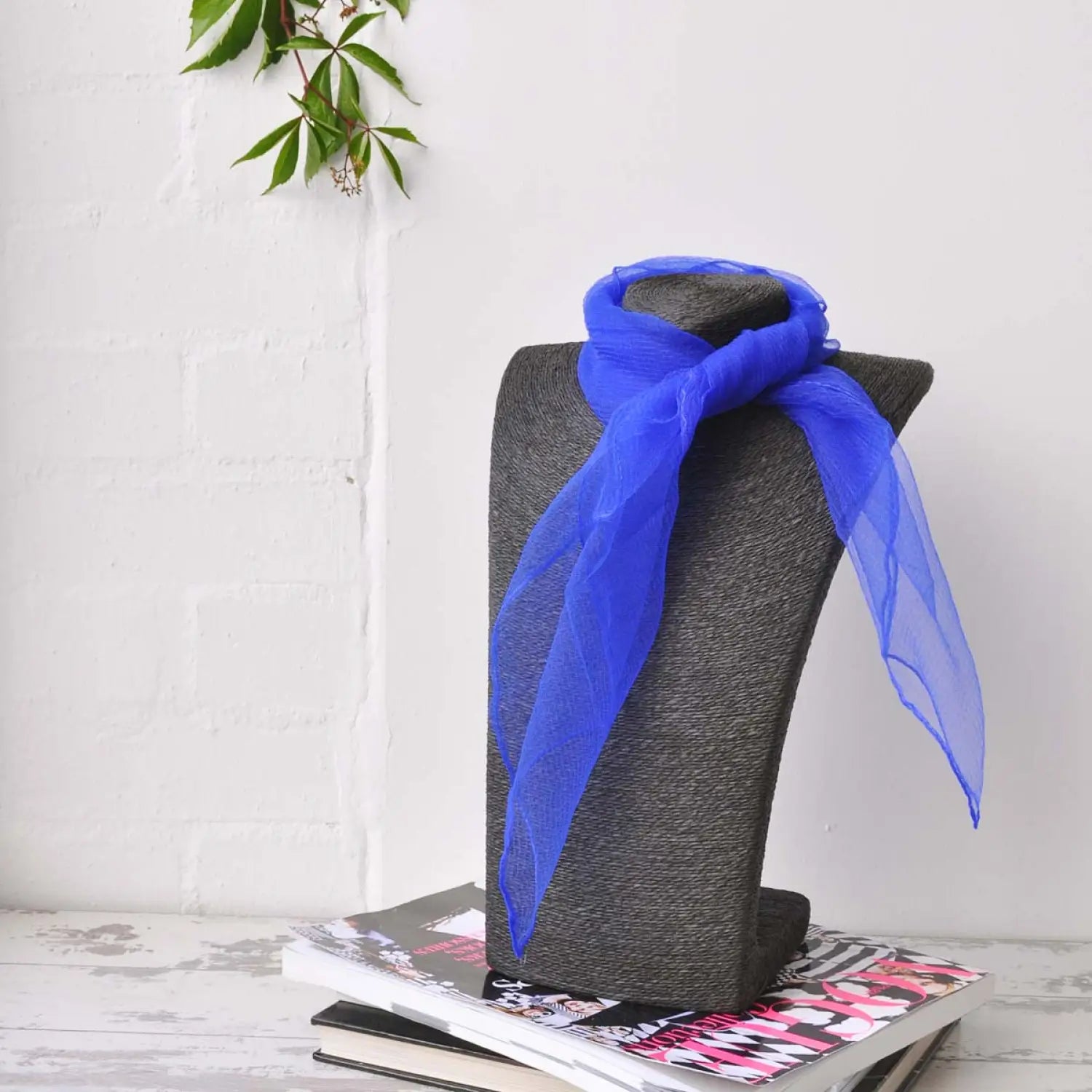 Blue chiffon square scarf tied to grey hat, retro organza style.