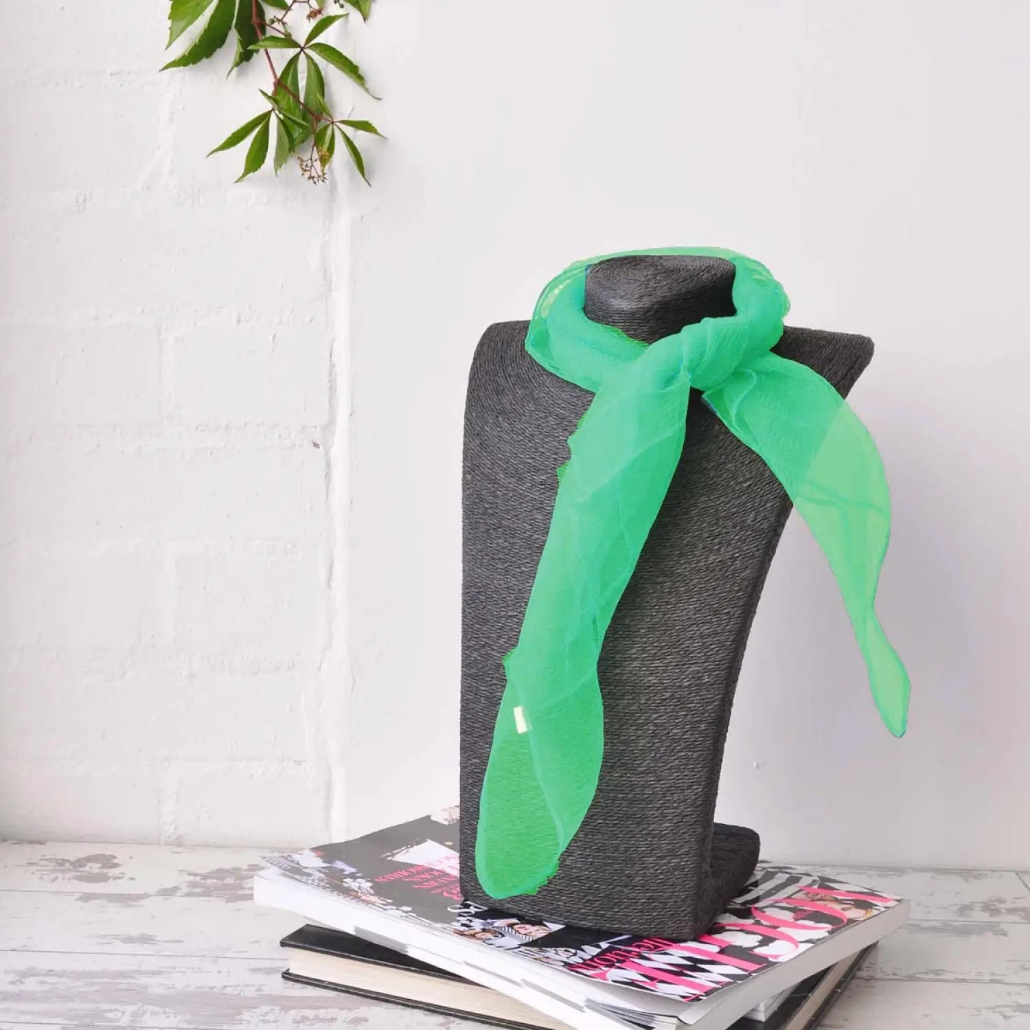 Green chiffon square scarf displayed on grey chair