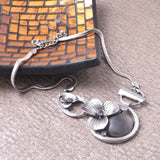 Chunky boho antique silver necklace with flower charm displayed on table