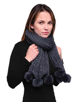 Woman wearing chunky knit winter scarf with pom pom accents