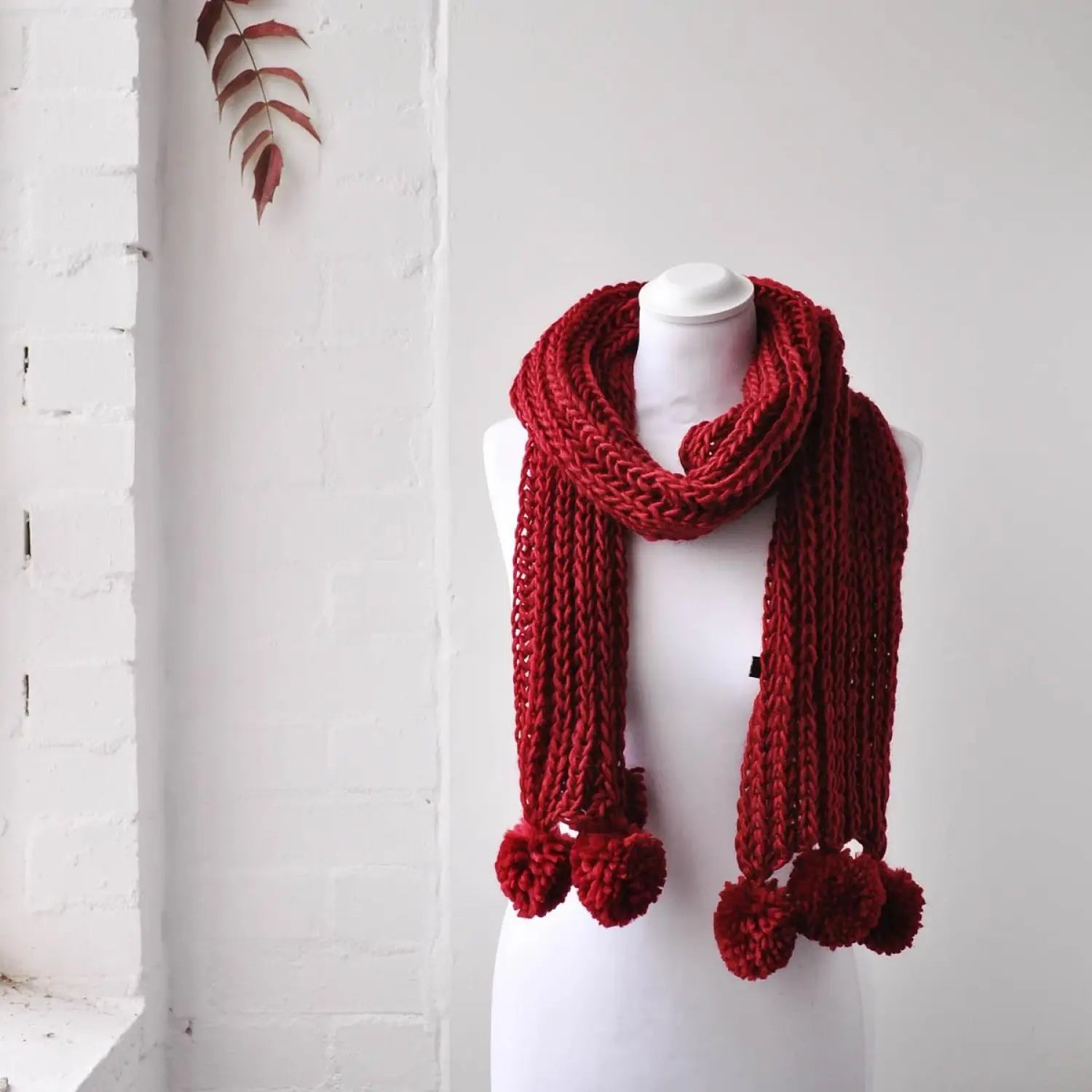 Chunky knit winter scarf with pom pom accents on mannequin