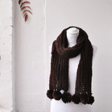 Chunky knit winter scarf with pom poms displayed on mannequin
