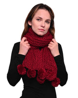 Chunky knit winter scarf with pom pom accents on woman in red scarf and black shirt