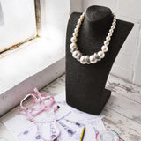 Chunky pearl necklace and glasses on a table.