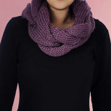 Woman wearing chunky plait knitted cowl snood scarf in purple for Autumn & Winter.
