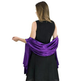 Elegant satin evening look: Woman in black dress with vibrant purple shawl draped over arms