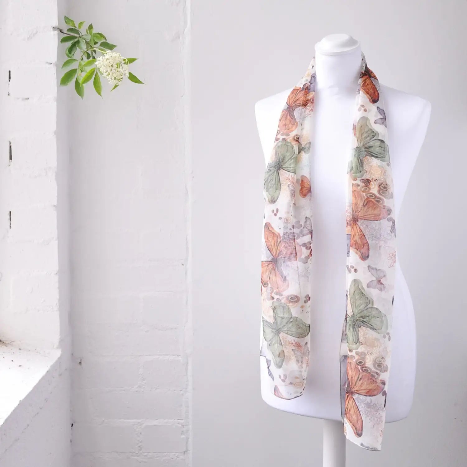 White mannequin displaying a floral print scarf from Colourful Large Butterfly Print Chiffon Scarf: Lightweight Elegance.