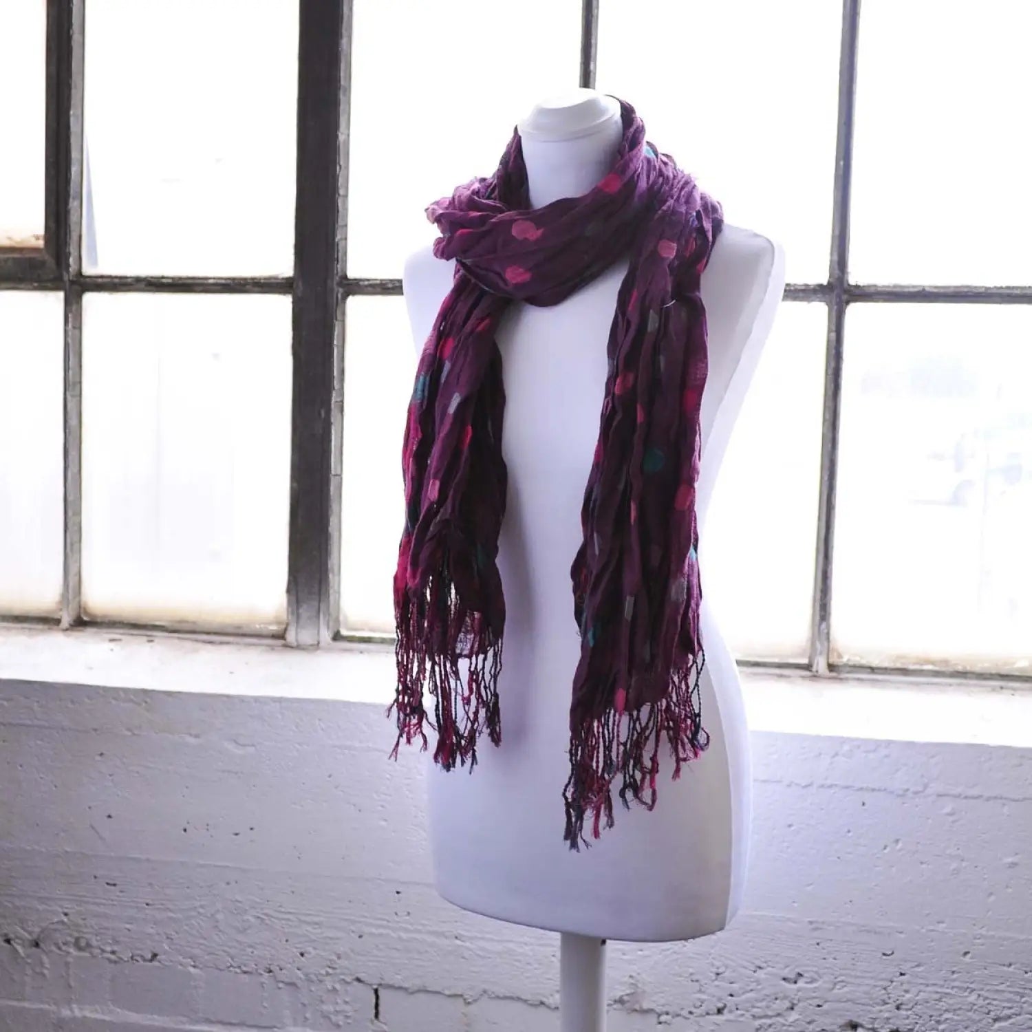 Polka dot print tasselled scarf displayed on mannequin by window