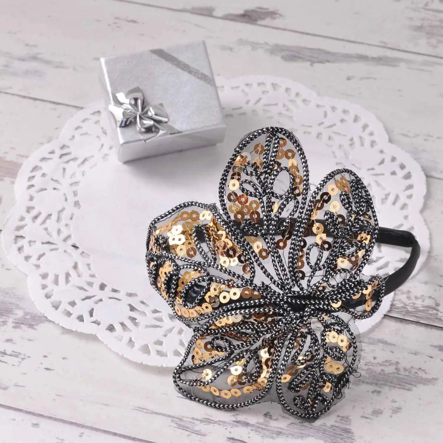 Black and gold flower hair clip on a white dog, part of Elegant Leaf Alice Headband with Spangle & Sequin Detailing product.