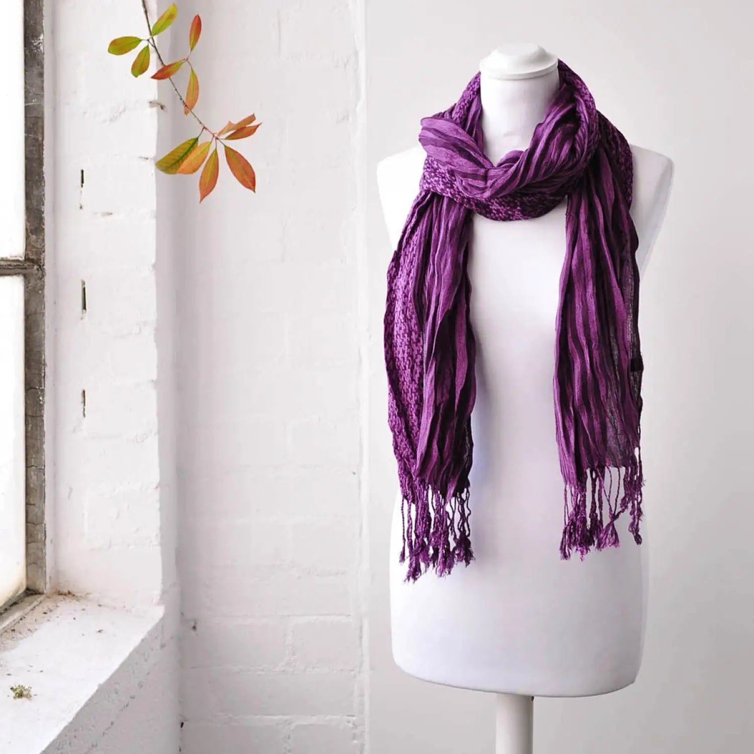 Elegant striped woven winter scarf on mannequin by window