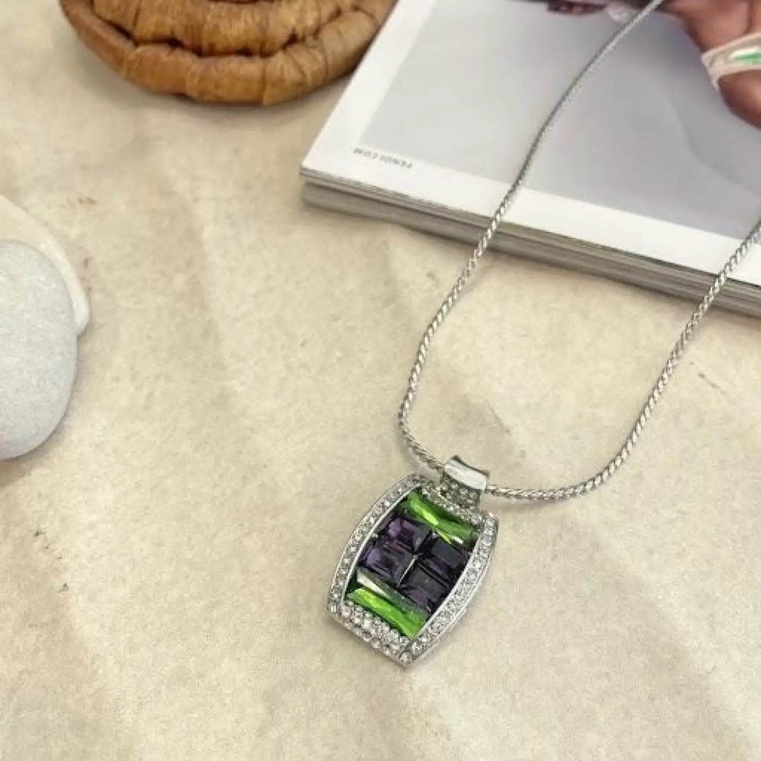 Emerald green necklace with woman’s hand holding a pendant