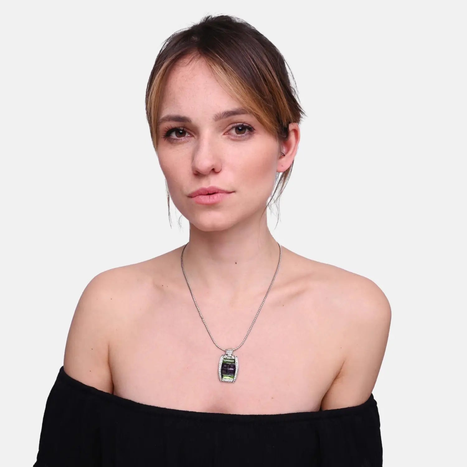 Woman wearing black top and emerald green diamante rectangle pendant necklace.