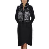 Woman in black dress and scarf with fringed trims, floral embroidery, soft texture.