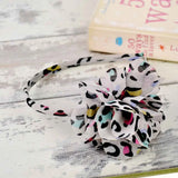 Chiffon 3D flower leopard print headband with white and black flower on white wooden table