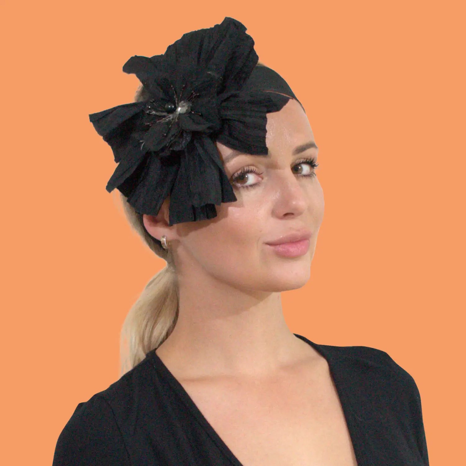 Woman wearing black large crinkled 3D flower headband with rhinestone applique.