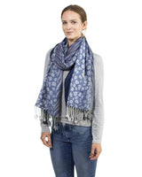 Woman wearing blue scarf with white flowers, zebra print tasselled oversized accessory.