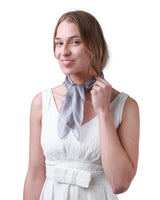 Woman in white dress tying silk small square scarf, 100% mulberry silk.