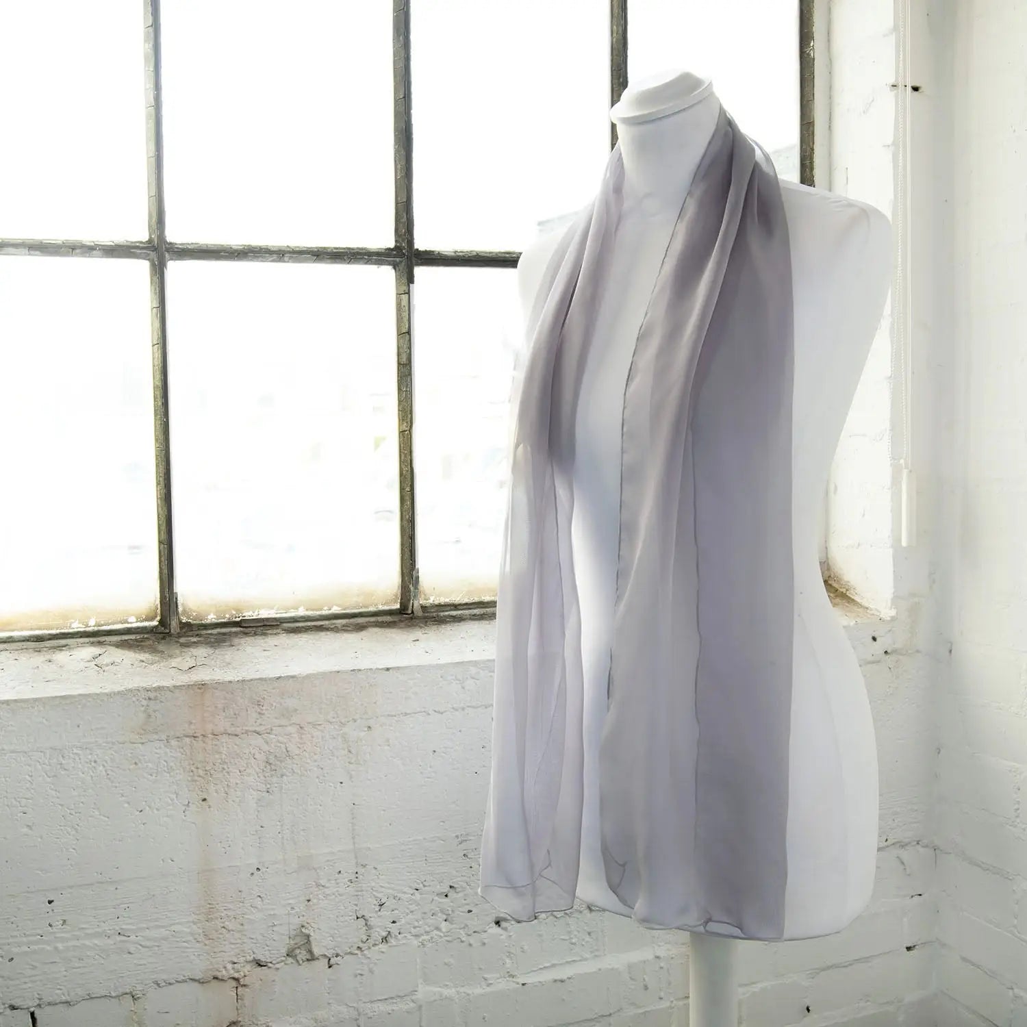 Classic plain chiffon scarf draped over mannequin near window.