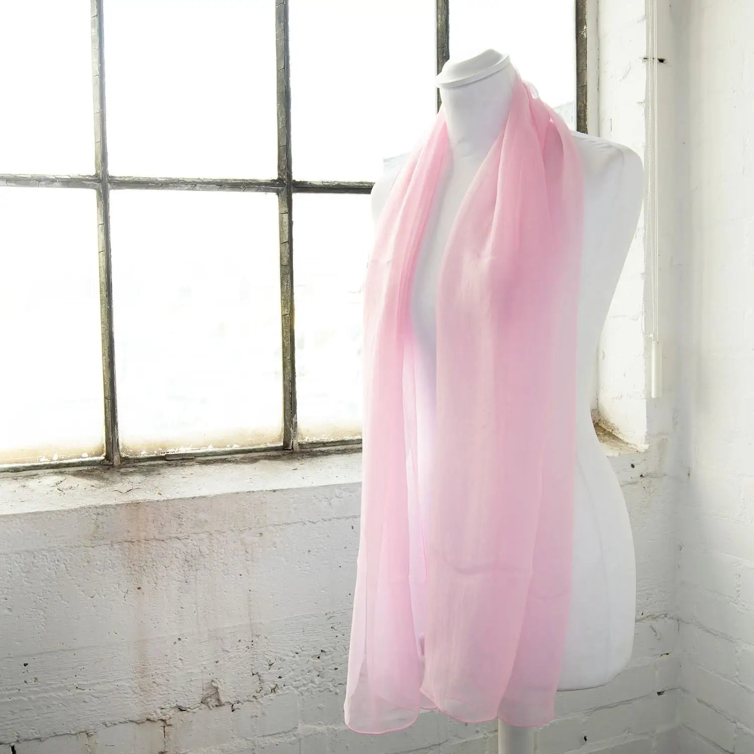 a pink scarf on a manne in front of a window