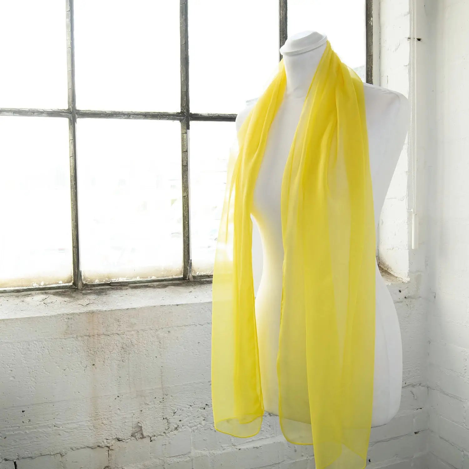 Classic plain chiffon scarf with yellow color hanging on mannequin.