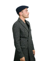A man wearing a black coat and hat, featuring Men’s Traditional Paperboy Flat Cap.