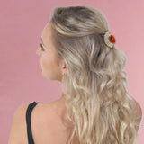 Blonde woman with red flower in hair wearing crystal fan hair claw.