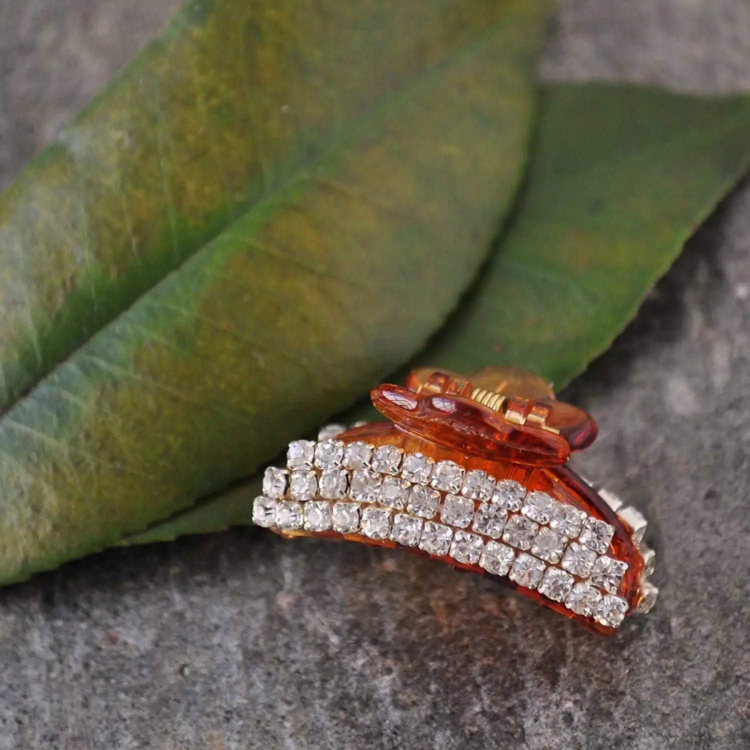 Orange stone diamond ring surrounded by smaller diamonds on hair claw accessory