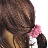 Woman wearing soft faux fur scrunchie with pink flower in hair.