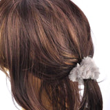 Woman with long brown hair wearing mini soft faux fur scrunchie with white feather