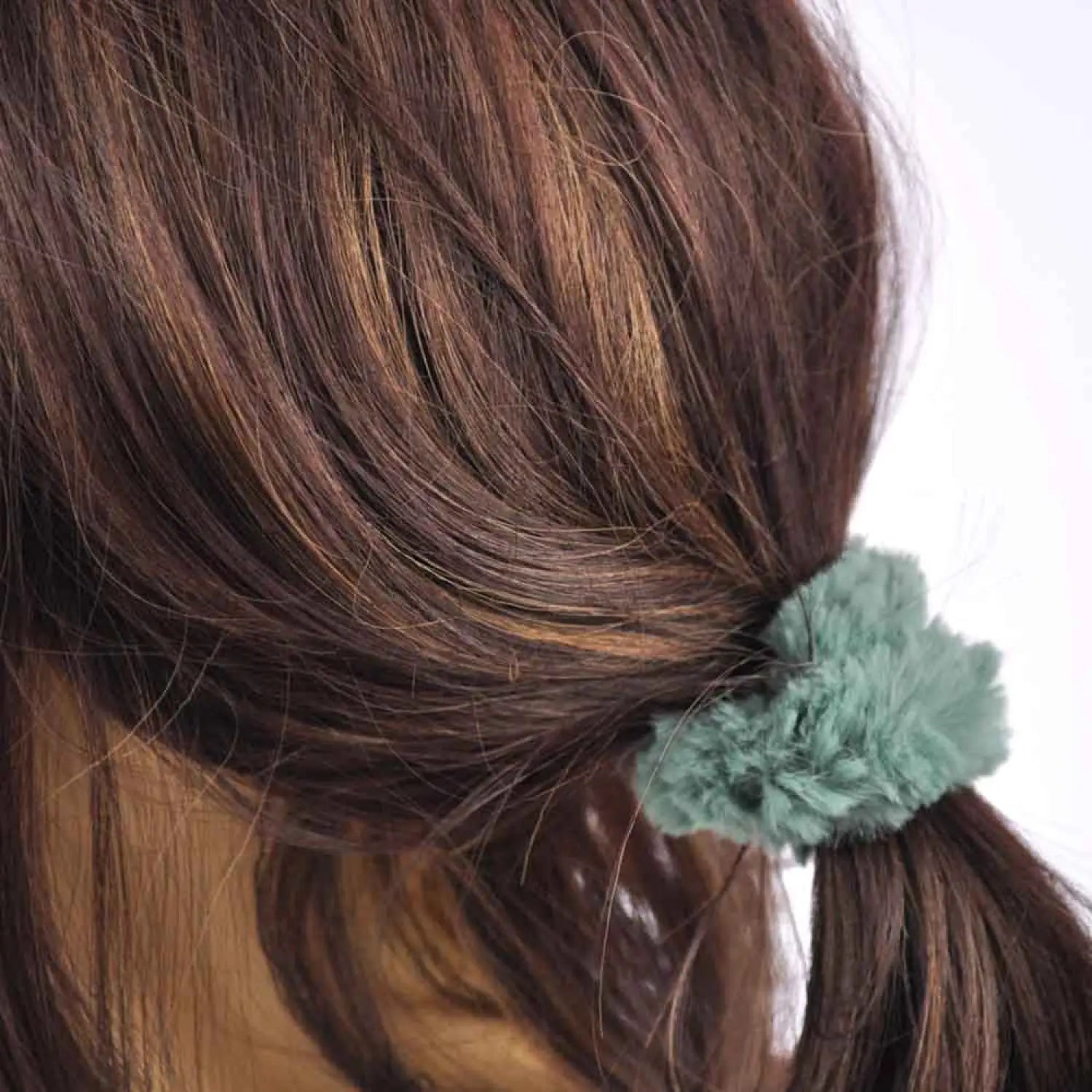 Woman wearing green hair clip with soft faux fur scrunchie.